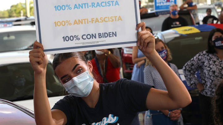 Wearing a face masks to reduce the risk posed by the coronavirus, Sophia Hildalgo (L) and Amore Rodriguez of Miami stay with their car decorated in Cubans for Biden paint as Democratic presidential nominee Joe Biden delivers remarks during a drive-in voter mobilization event at Miramar Regional Park October 13, 2020 in Miramar, Florida. Photo by Chip Somodevilla/Getty Images